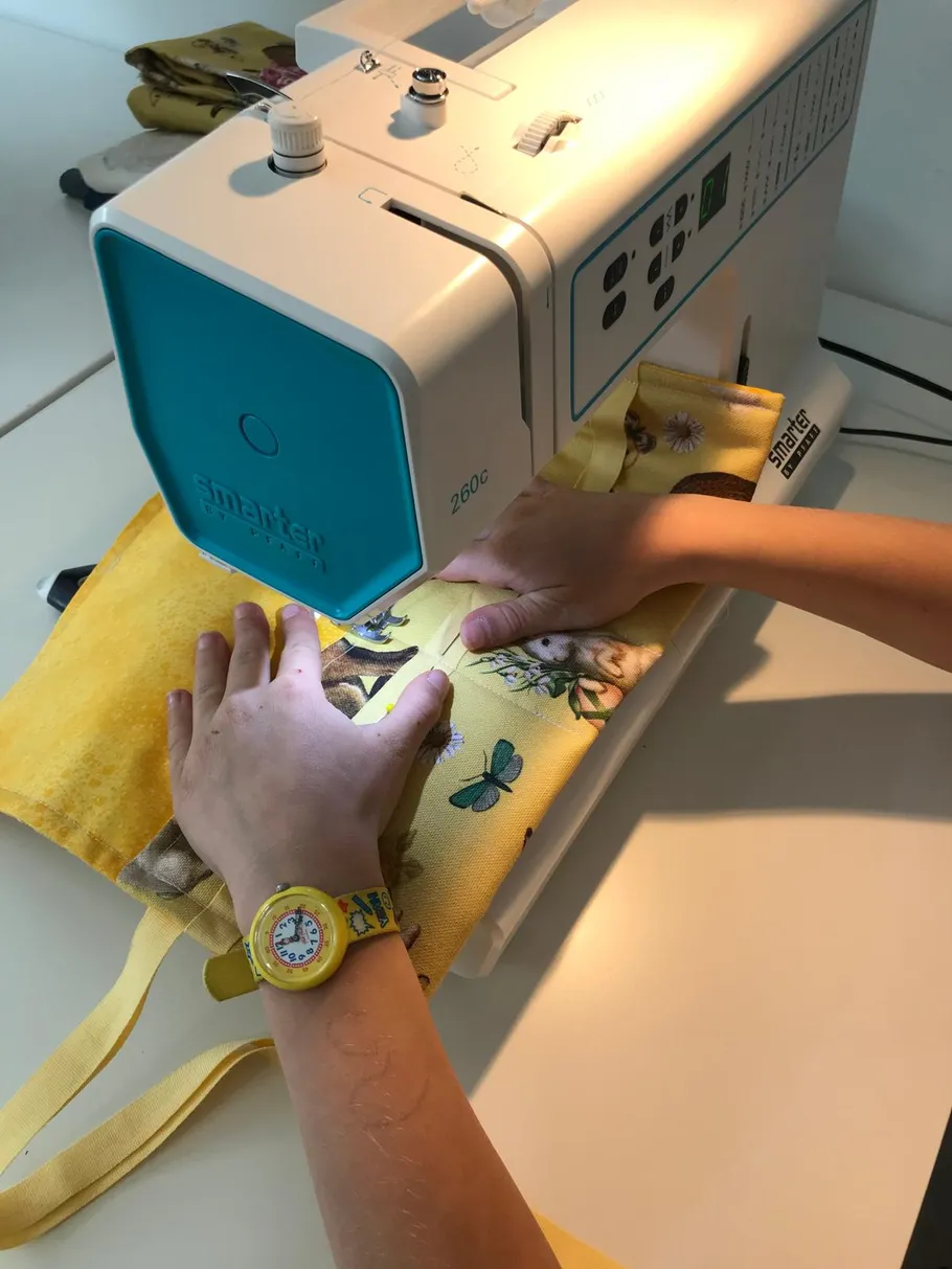 Hände nähen gelben Stoff mit einer Maschine.