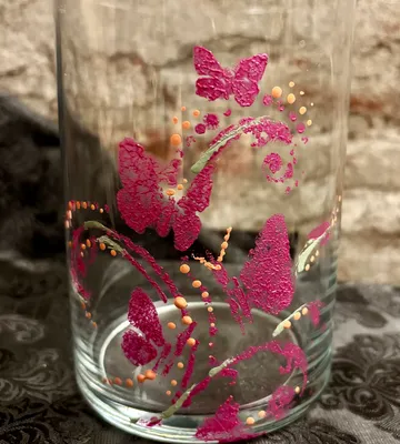 Glass with pink butterfly design on table.