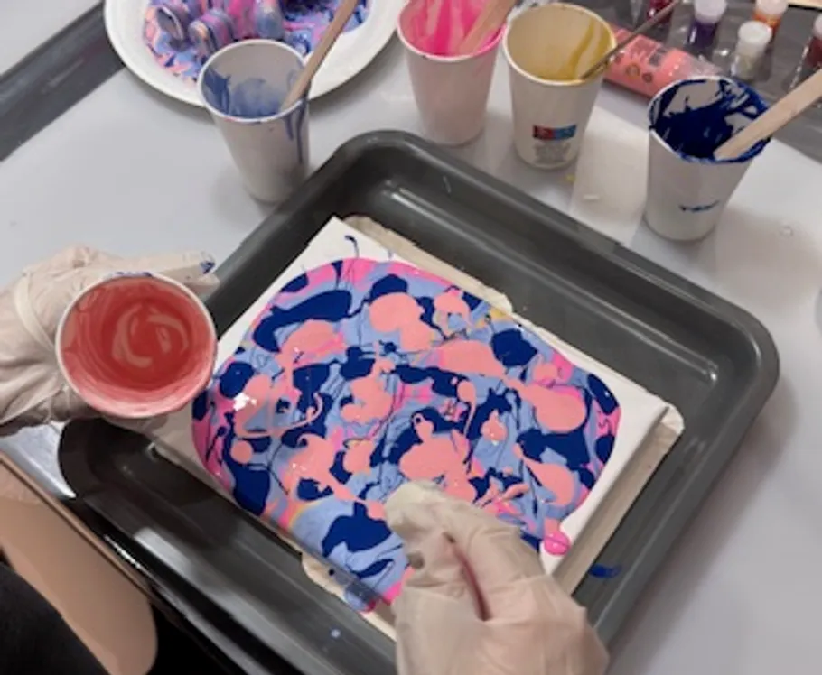 Fluid art painting, hands pouring paint, canvas.