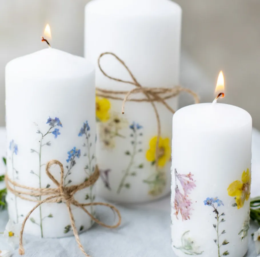 Three floral decorated candles on a table.