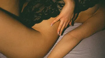 Person in Spitzenwäsche liegend auf Bett.