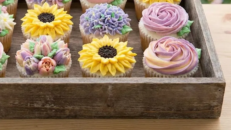 Cupcakes mit Blumendesigns in Holztablett.
