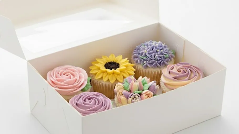 Dekorative Cupcakes in einer weißen Schachtel.