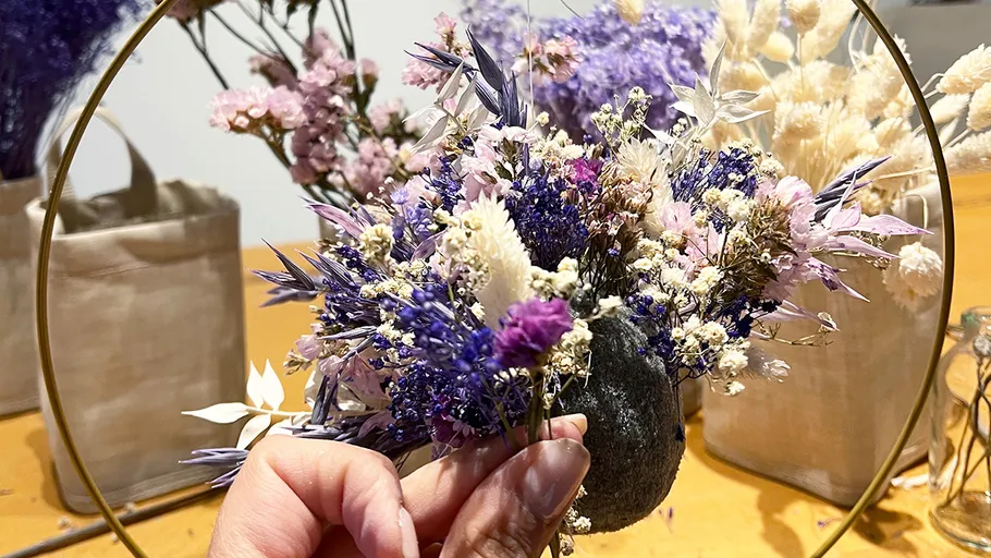 Hand arranging dried flowers in a frame.