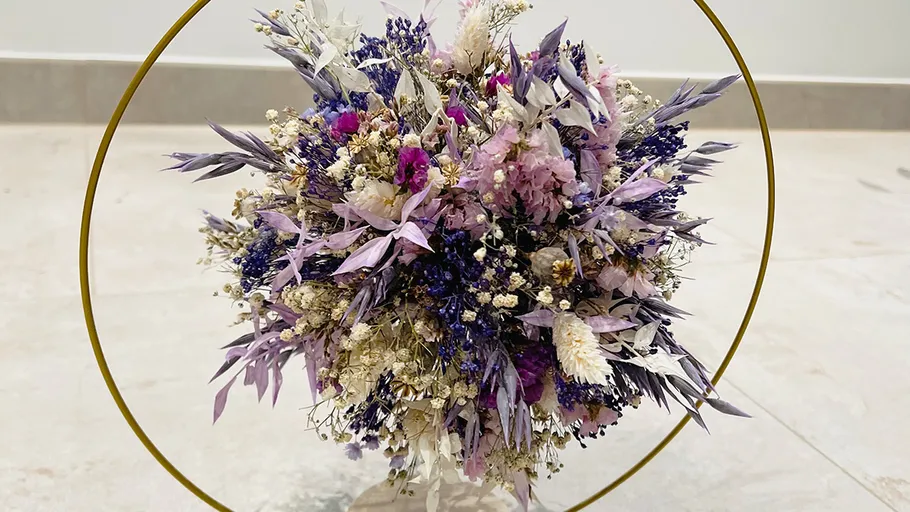 Colorful dried bouquet inside golden hoop on floor.