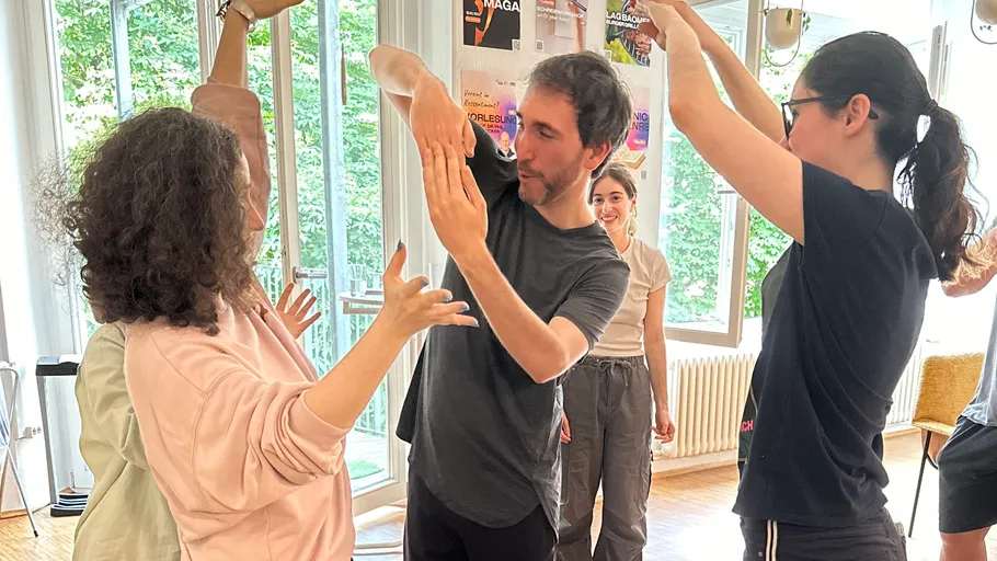 Group practices dance moves indoors, smiling.