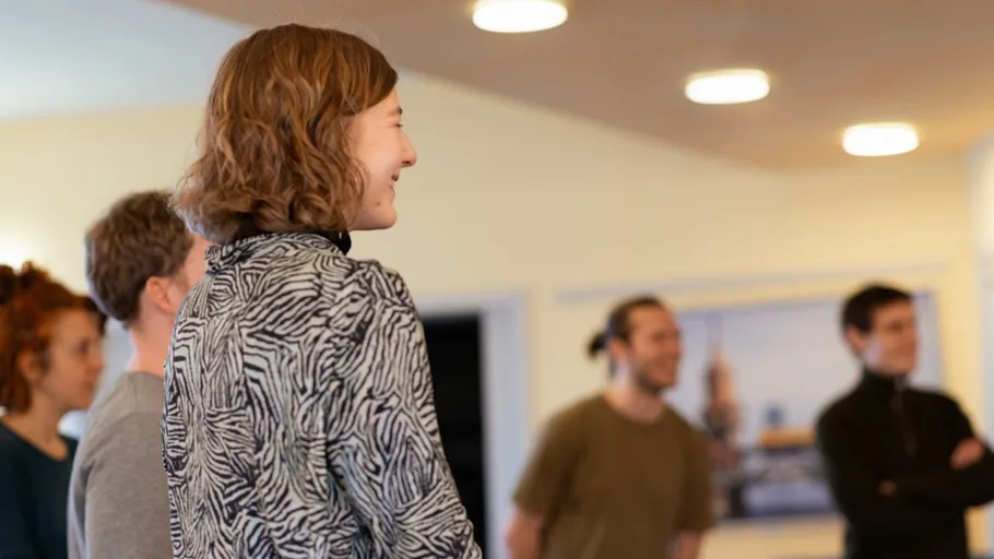 People standing indoors, smiling and talking.