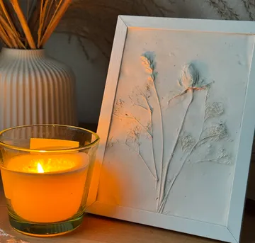Framed botanical imprint beside a lit candle.