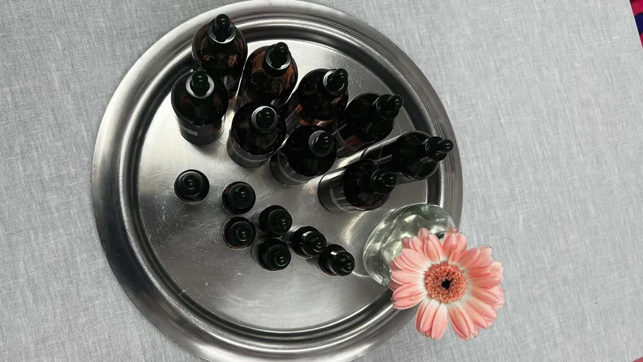 Bottles arranged on tray with flower nearby.