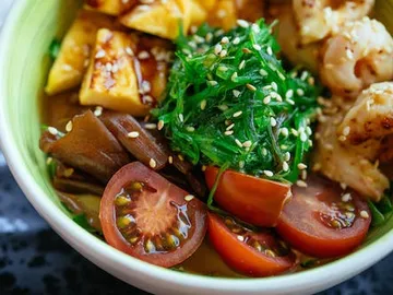 Bowl with various ingredients: vegetables, seaweed, and shrimp.