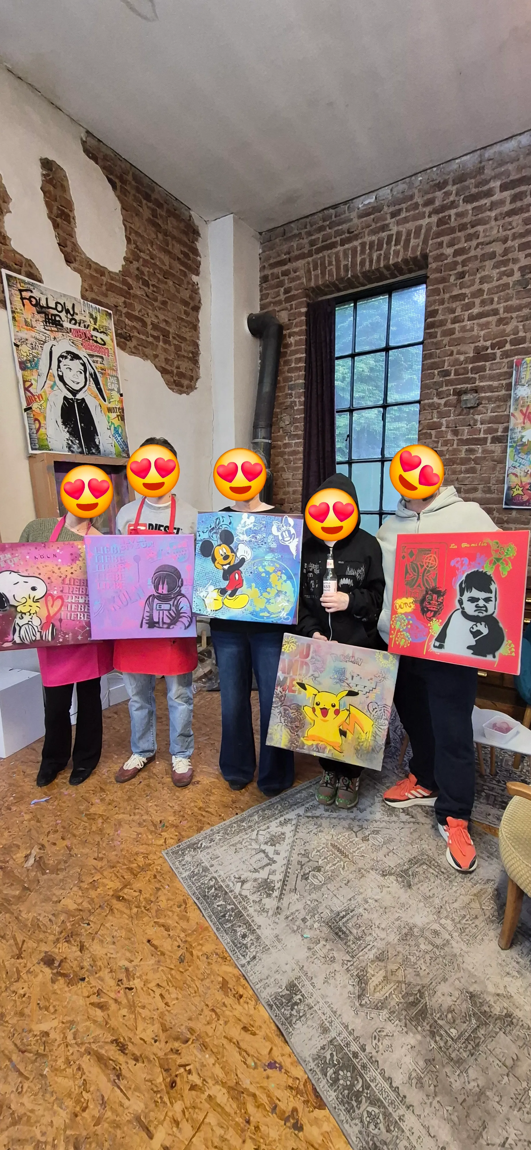 Personen halten Gemälde in Backsteinraum.