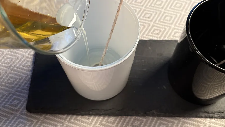 Pouring liquid into a white cup, wick inside.