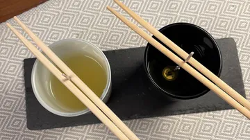 Zwei Becher mit Stäbchen auf einem Tablett.