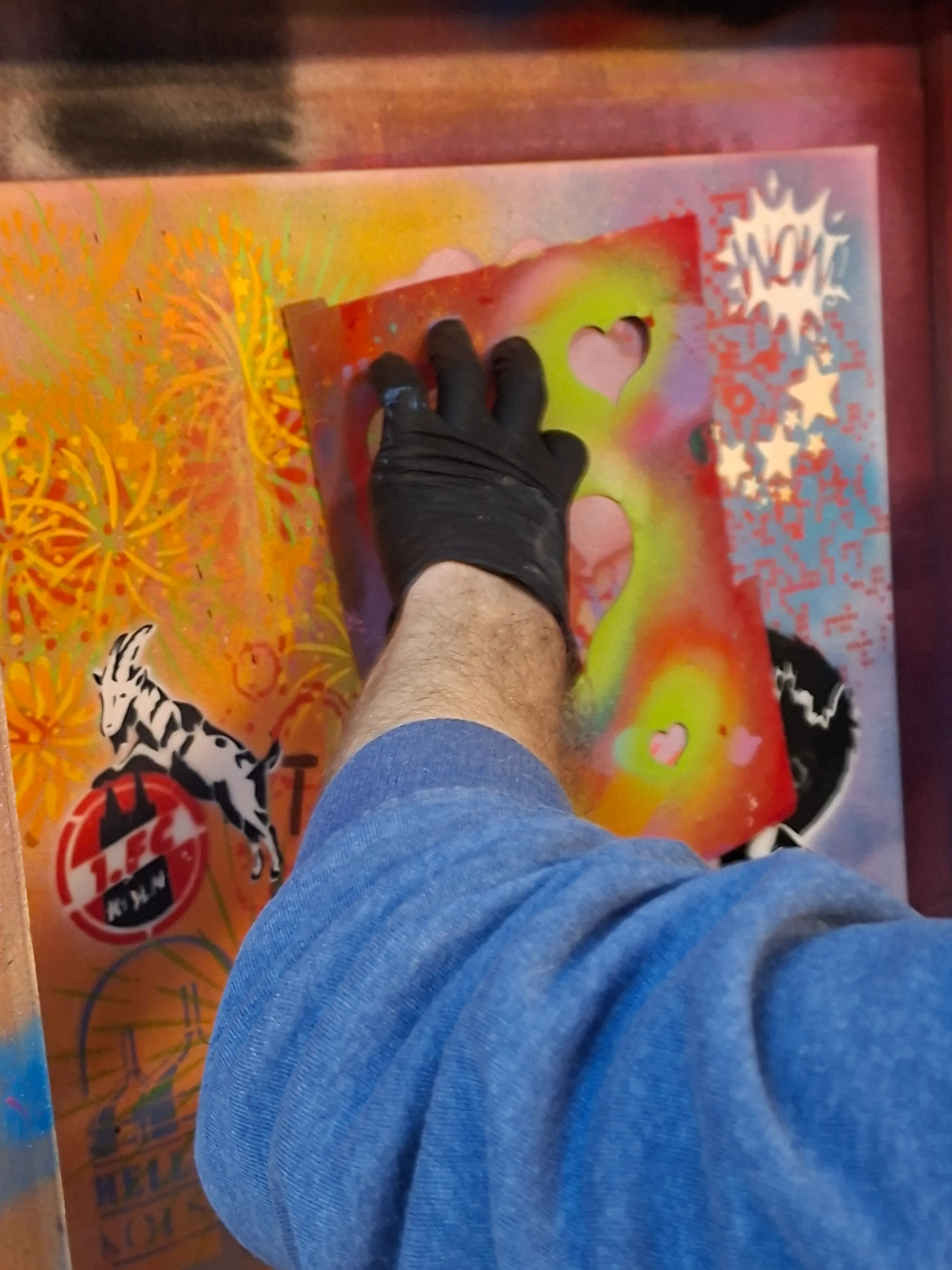 Hand sprüht bunte Schablone auf Leinwand.