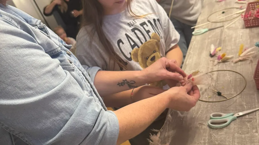 Two people crafting with feathers on a table.