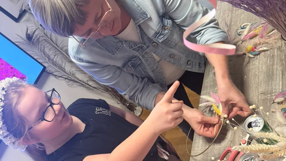 Two people crafting with tools on a table.