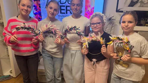Five girls hold decorative wreaths indoors.