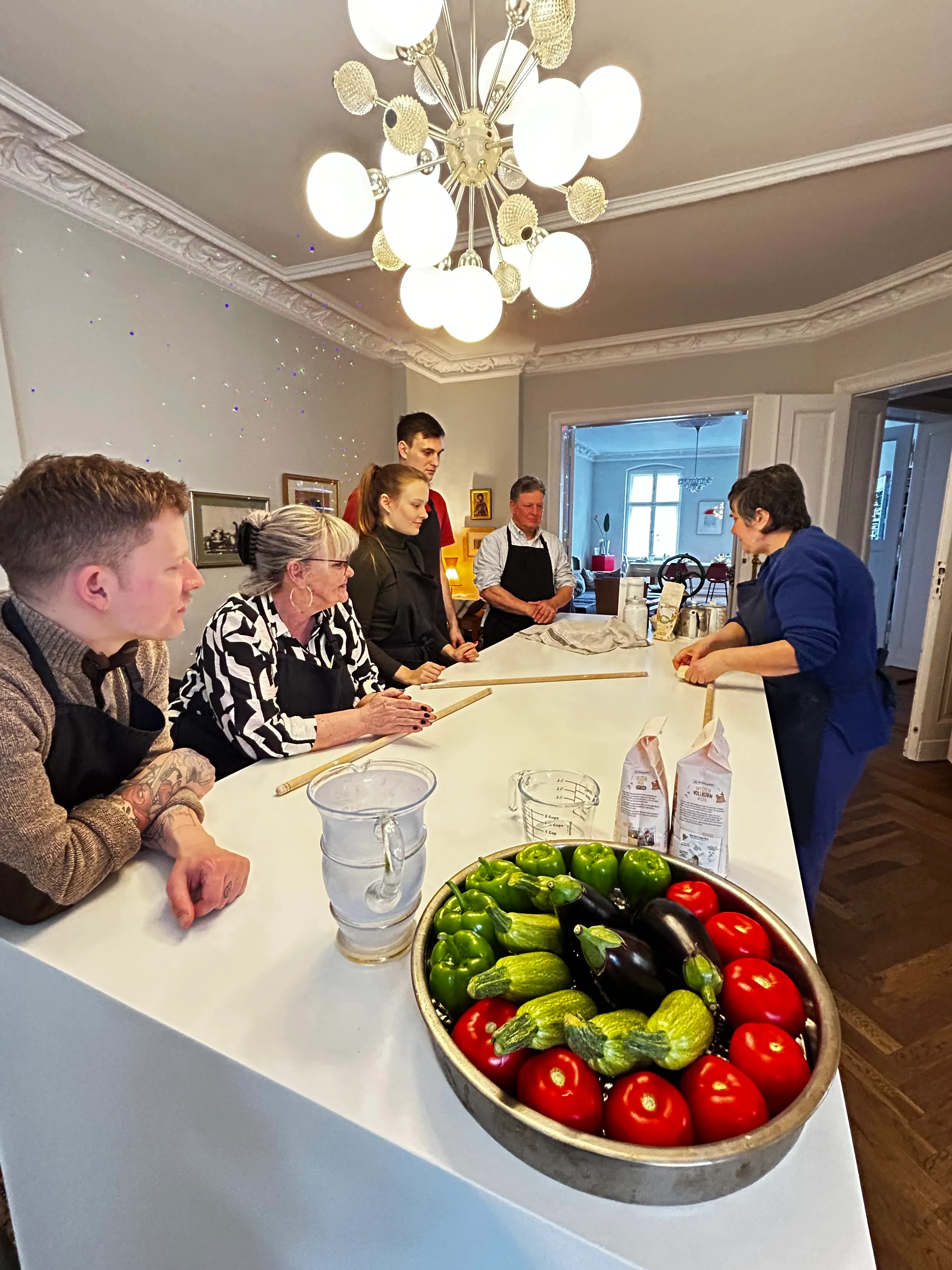 Gruppe beobachtet Kochvorführung in moderner Küche.