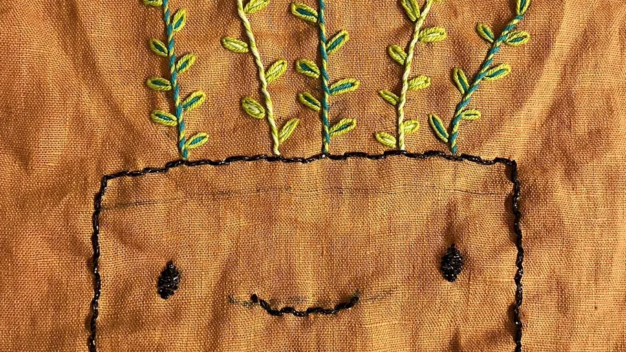 Embroidery of planter with smiling face.