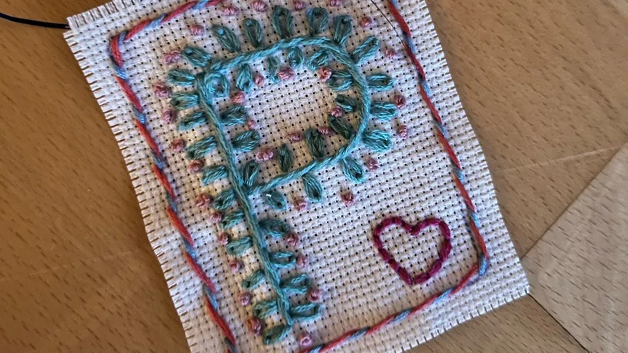 Stickerei mit blauem Buchstaben P, rosa Herz.