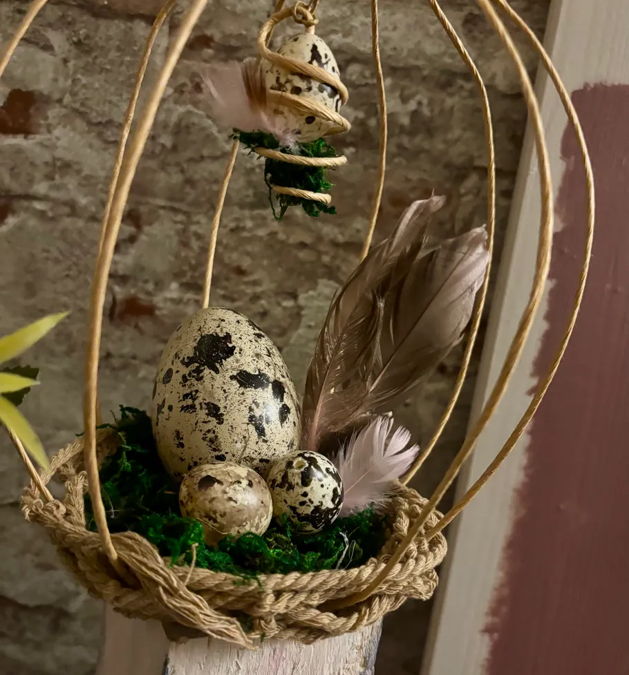 Speckled eggs in decorative nest with feathers.
