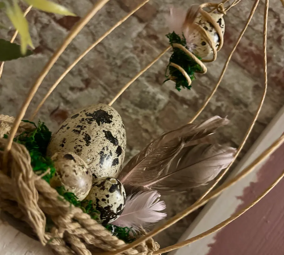 Decorative eggs and feathers in woven basket.