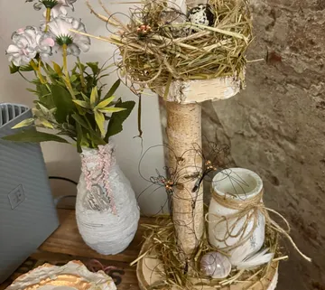Dekoratives Nest mit Eiern auf Holzständer.