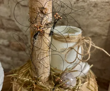 Wire flowers on a birch tree with a candle.