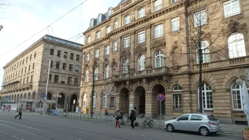 People walking by historic buildings on street.