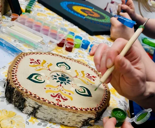 Person painting mandala on wood in workshop.