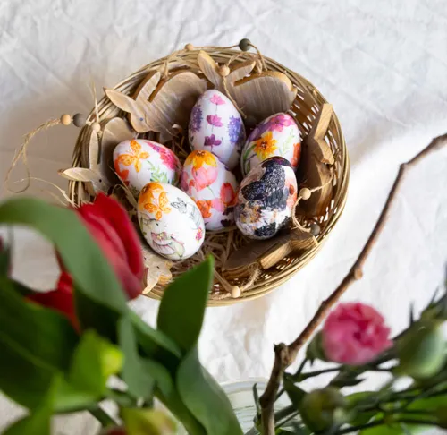 Decorated eggs in a wicker basket, surrounded by flowers.