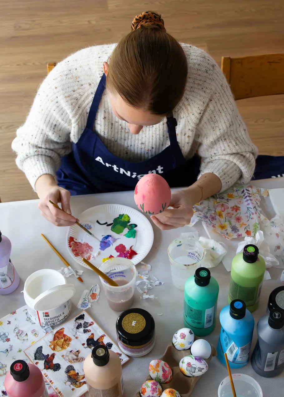 Person painting Easter egg at a table.