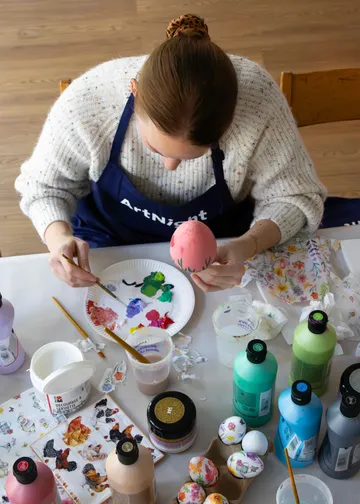 Person painting an egg with colorful paints.