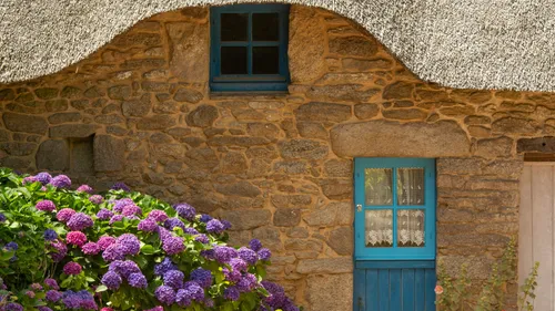 Stone cottage with blue doors and flowers.