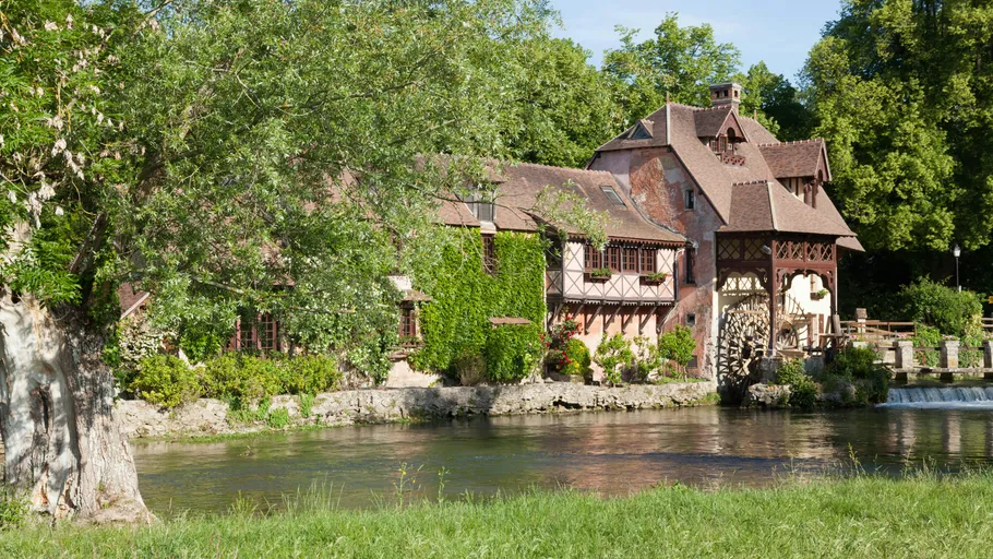 Old mill and river in lush greenery.