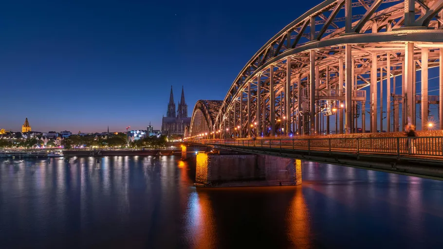 Bridge spanning river with city skyline illuminated.