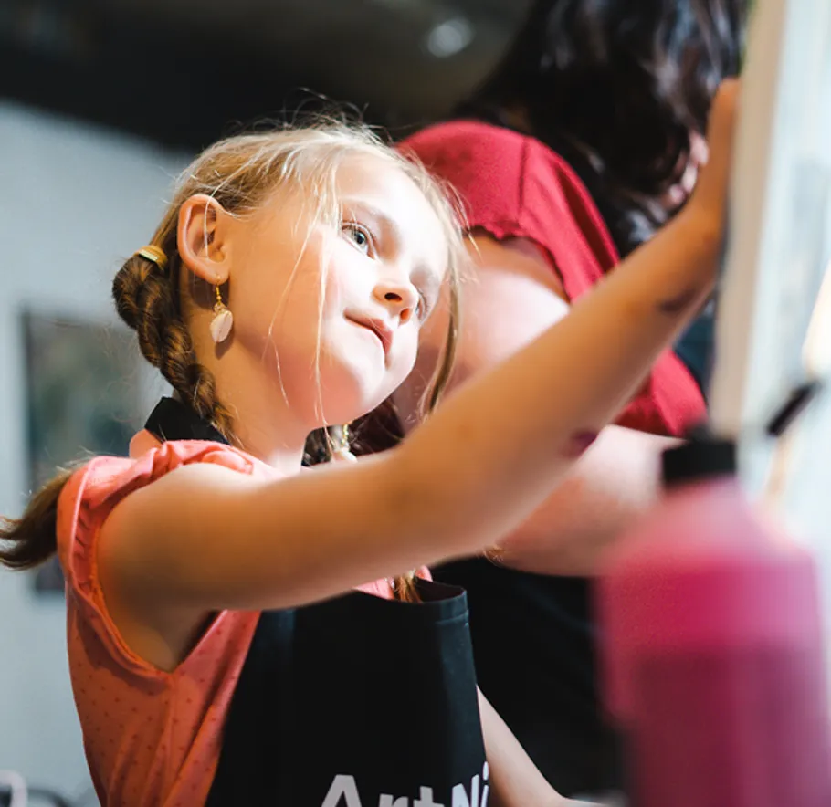Child painting on a canvas indoors.