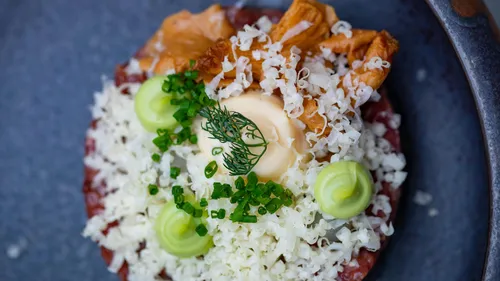 Gourmet dish with toppings and herbs, plated artistically.