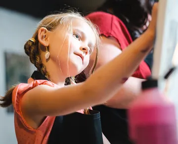 Child painting on canvas indoors.