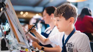 Boy painting with focus in art class.