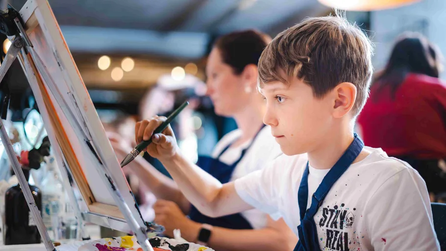 Child painting with brush, focused in studio.