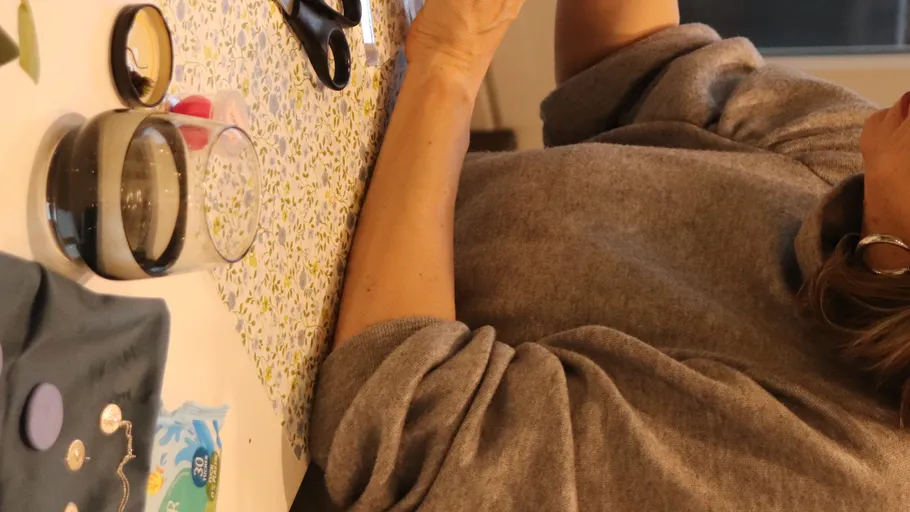 Person crafting buttons at a table indoors.