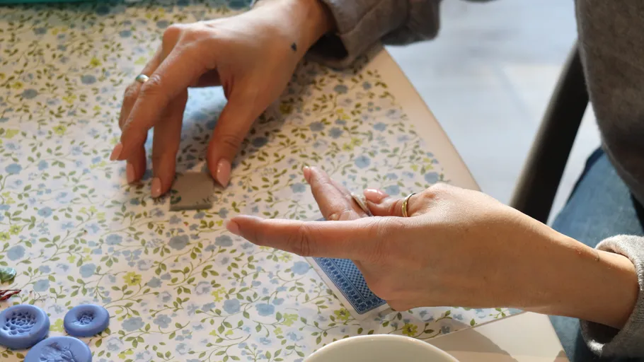 Hands crafting clay on floral table.
