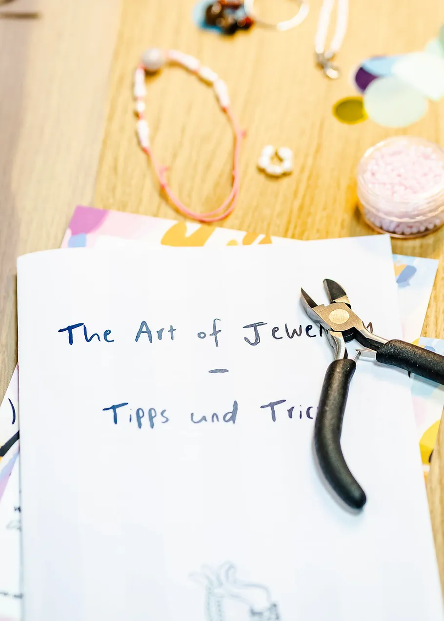 Jewelry tools and booklet on wooden surface.