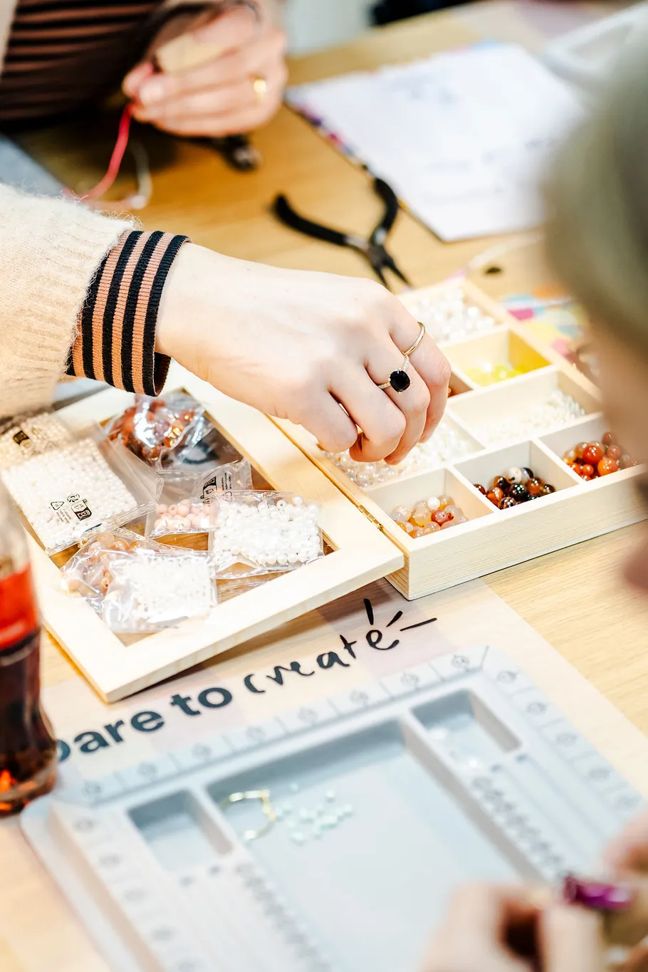 Hands organizing beads on a crafting table.