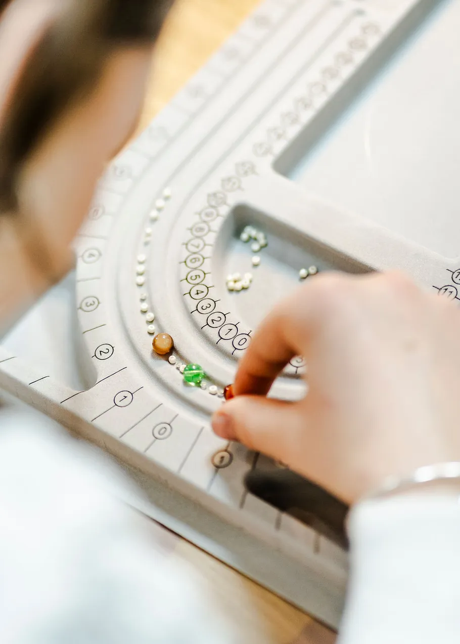 Person arranging beads on a gray beading mat.