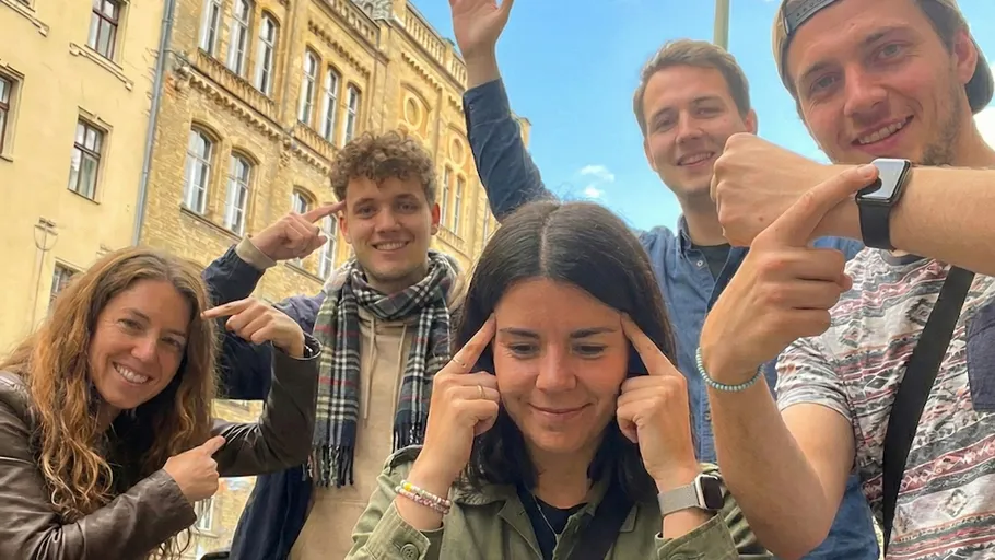 Five people posing playfully outside a building.