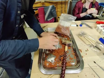 A person uses clay to form an object in a workshop environment.