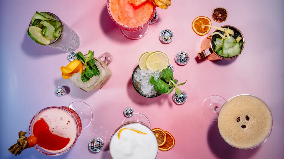 Assorted cocktails arranged on pink-purple surface.