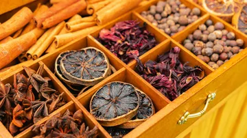 Assorted dried spices organized in a wooden box.